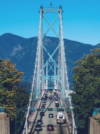 Cars on bridge in city against blue sky