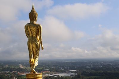 Statue of buddha against sky and cityscape