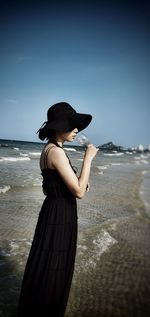 Woman having wine at beach against clear sky