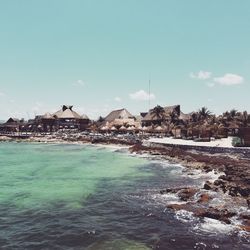 Scenic view of sea by buildings against sky