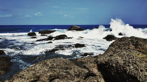 Scenic view of rocks on shore against sky