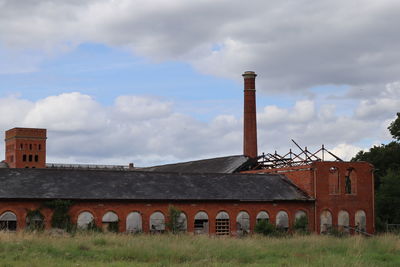 Old factory on field against sky