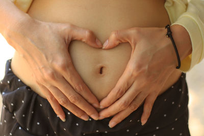 Body care, pregnancy diet concept, female hands forming heart shape on the stomach