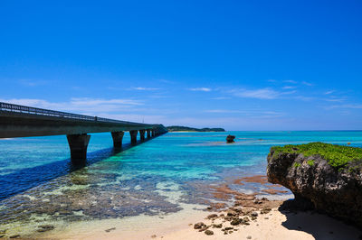 Bridge over sea against blue sky