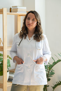 Portrait of young woman standing against wall