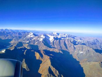 Aerial view of snowcapped mountains against blue sky