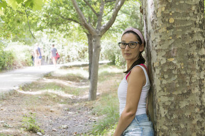 Portrait of woman standing by tree