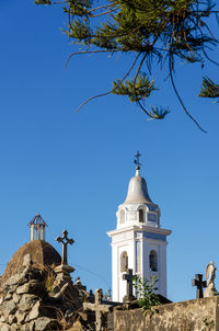 Low angle view of bell tower at cemetery against clear blue sky