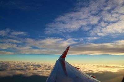 Close-up of airplane wing against cloudy sky