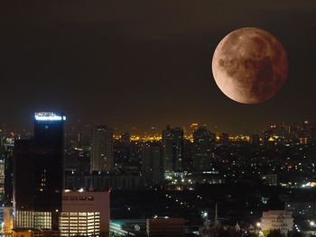 Illuminated cityscape against sky at night