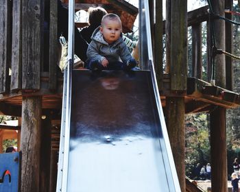 Cute boy sitting on slide in playground