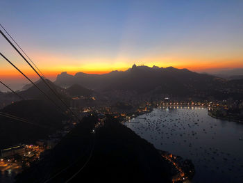 Silhouette city by mountains against sky during sunset