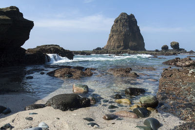 Rock formation on beach against sky