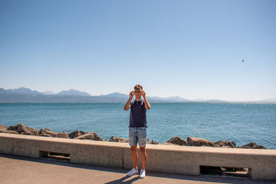 Rear view of woman standing on beach against clear sky