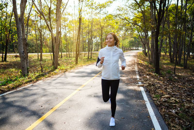 Full length of woman standing on footpath by road