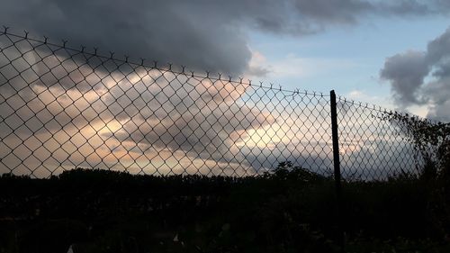 Fence on field against sky during sunset