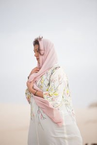 Woman wearing hijab standing at beach