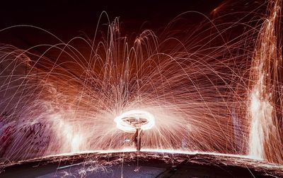 Person making wire wool against sky at night