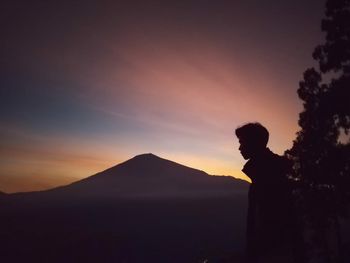 Silhouette man looking at mountain against sky during sunset