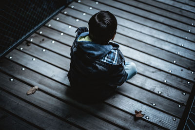 Rear view of boy sitting on pier