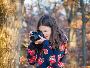 Portrait of woman photographing with autumn leaves