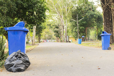 Garbage bin by trees against blue sky