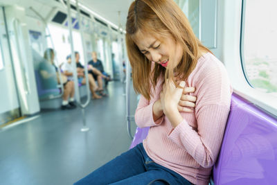 Woman with chest pain sitting in train