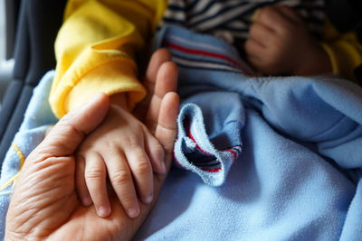 Cropped hand of mother holding babys hand