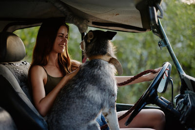 Portrait of young woman with dog in car