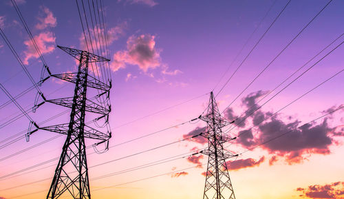 Low angle view of silhouette electricity pylon against dramatic sky