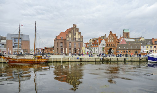 Boats moored in canal by buildings against sky in city