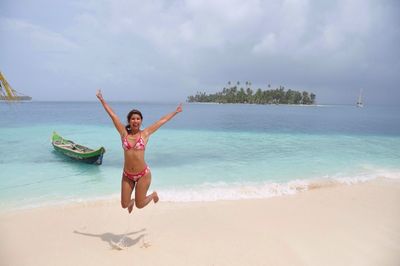 Young woman jumping into air on beach