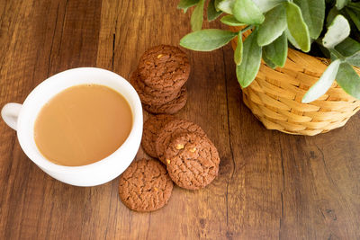 A cup of coffee and cookies on wooden table abd black background