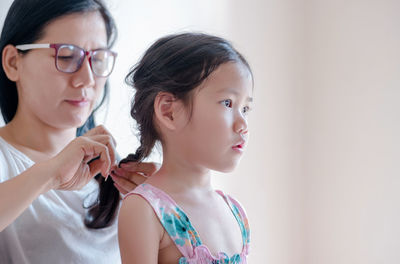 Close-up of mother braiding daughter's hair