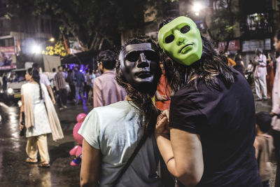 Midsection of woman holding mask at night during halloween