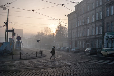 Person walking at city street during sunset