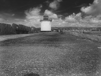 Lighthouse on field against sky