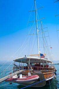 Sailboats moored in sea against clear blue sky