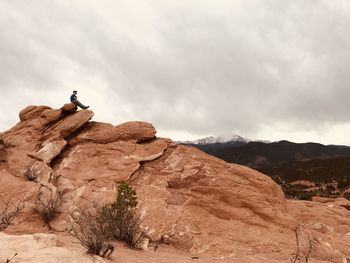 Low angle view of man standing on rock against sky