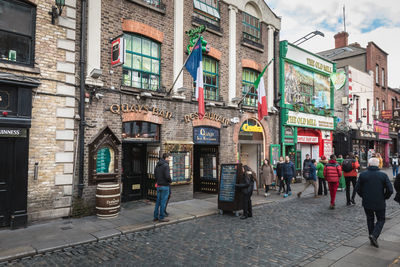 People walking on street amidst buildings in city