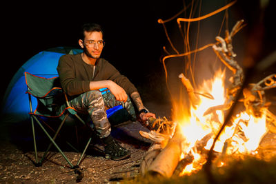 Portrait of man sitting on fire at night