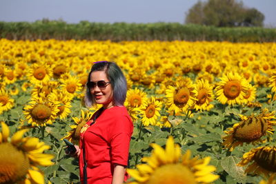 Portrait of woman standing amidst yellow flowering plants on field