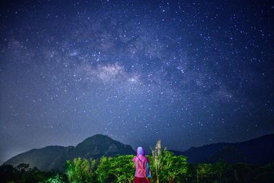 Rear view of girl standing against star field at night