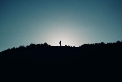 Silhouette man standing on field against clear sky