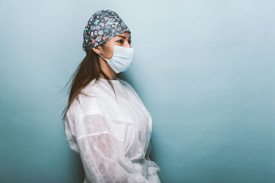 Side view of doctor wearing mask standing against wall