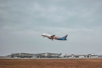 Airplane flying over land against sky