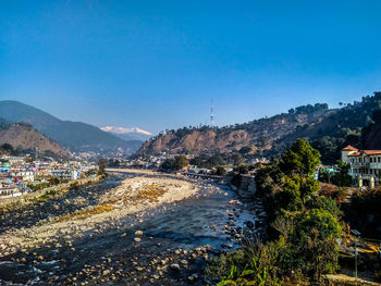 Scenic view of buildings and mountains against clear blue sky