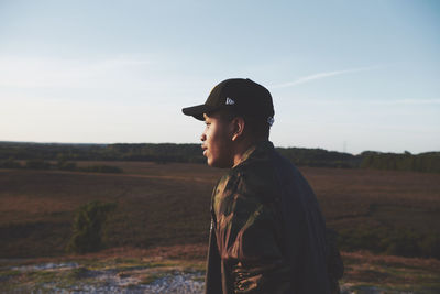 Side view of young man looking away on field