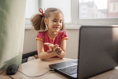 Girl looking away while sitting on table