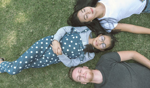 Directly above shot of friends napping on field at public park